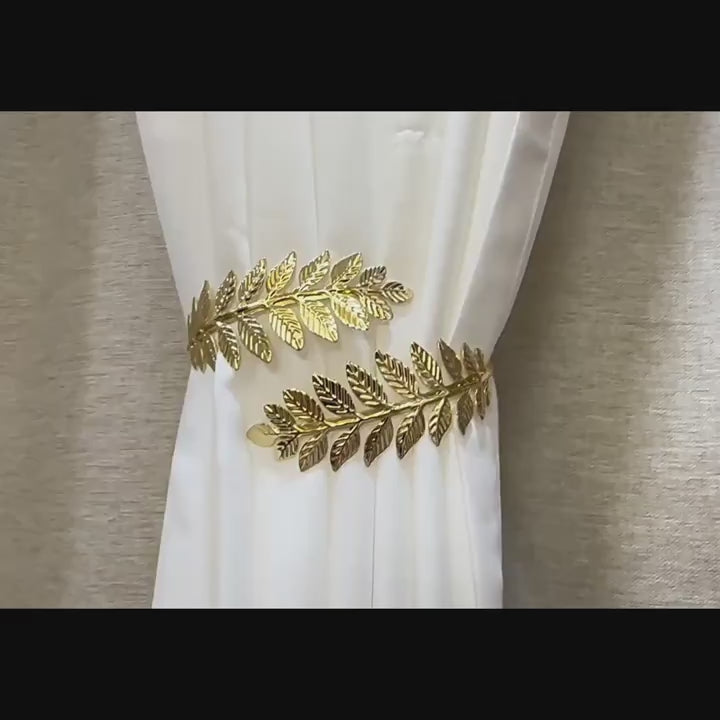 Elegantiški metaliniai užuolaidų laikikliai, laikantys baltą užuolaidą